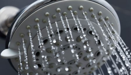 Total Water Solutions. Water pouring out of a shower head.