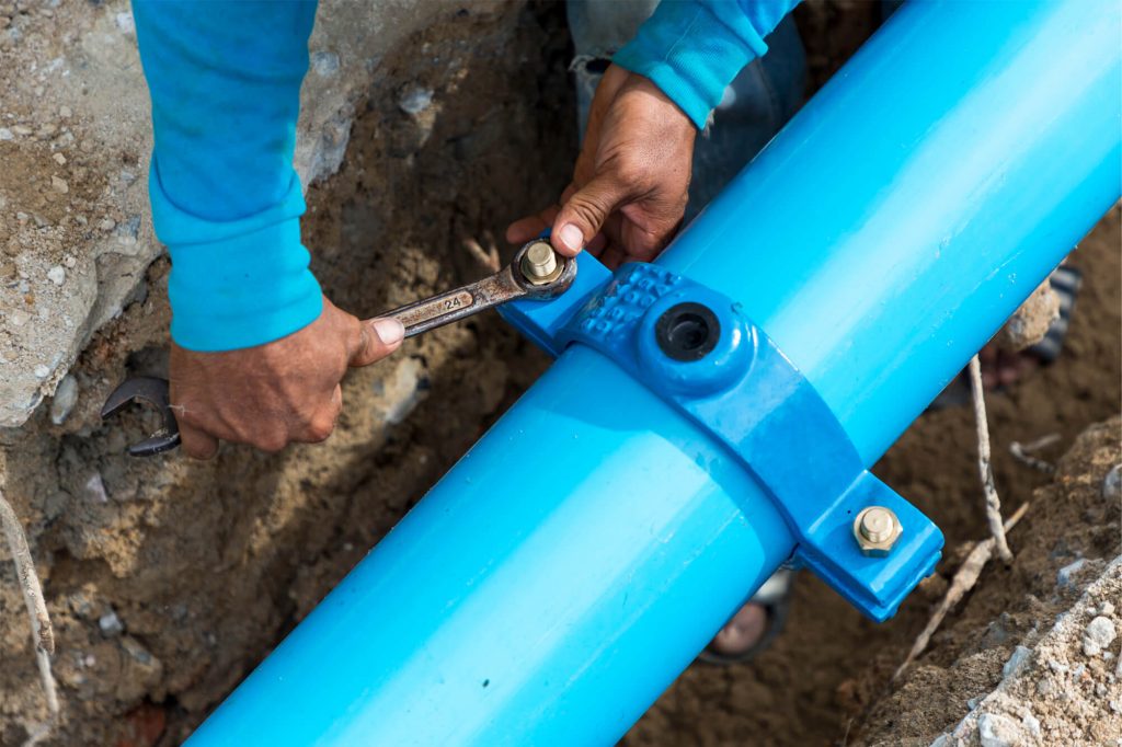 Man tightening a bolt on a clean water pipe